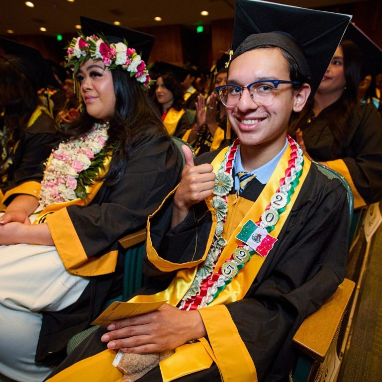Graduates in caps and gowns Graduates in caps and gowns at a ceremony, one giving a thumbs-up and wearing a lei.